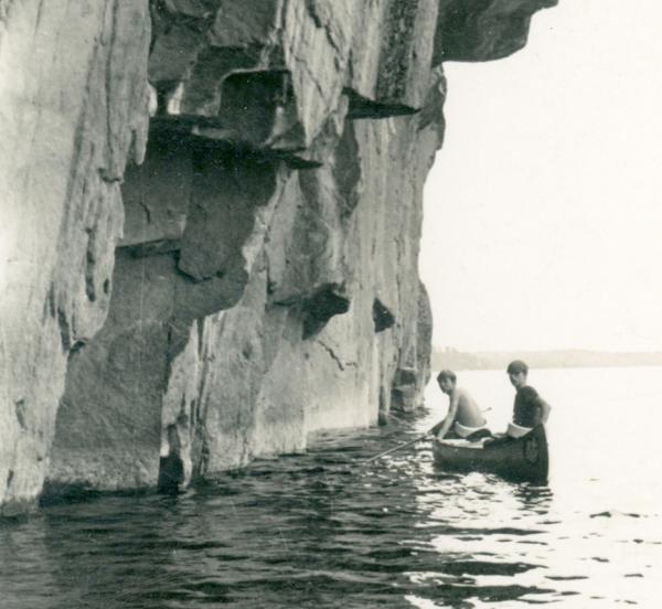 Two boys paddling by a cliff