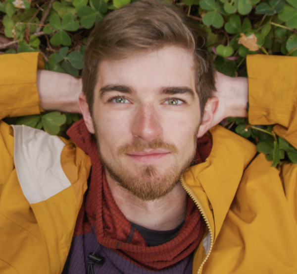Alex Haraus laying in grass in yellow jacket