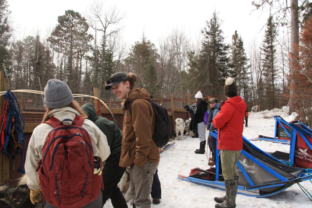 People standing in a sled dog kennel, ready to sled.