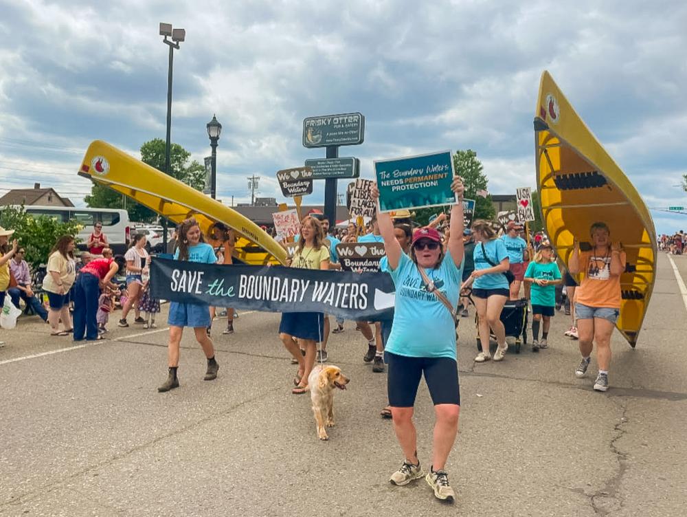 Supporters walking down street with signs and canoes
