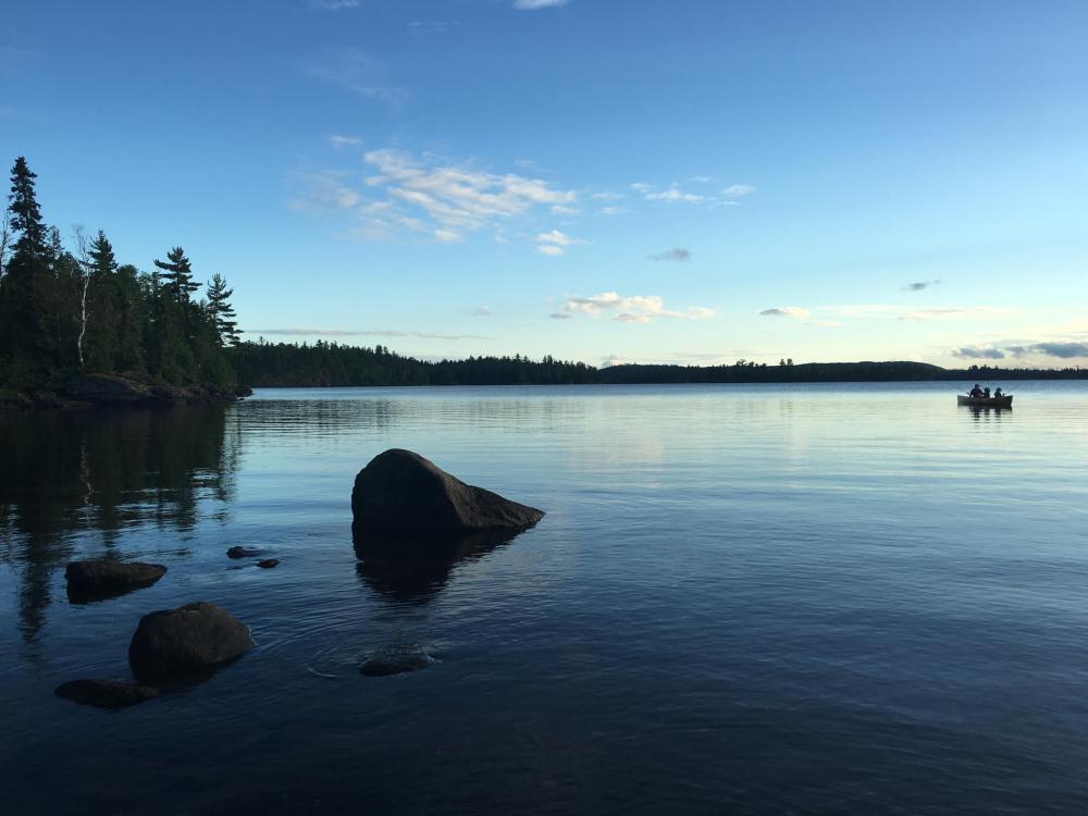 A canoe paddles out toward the middle of a lake in the Boundary Waters