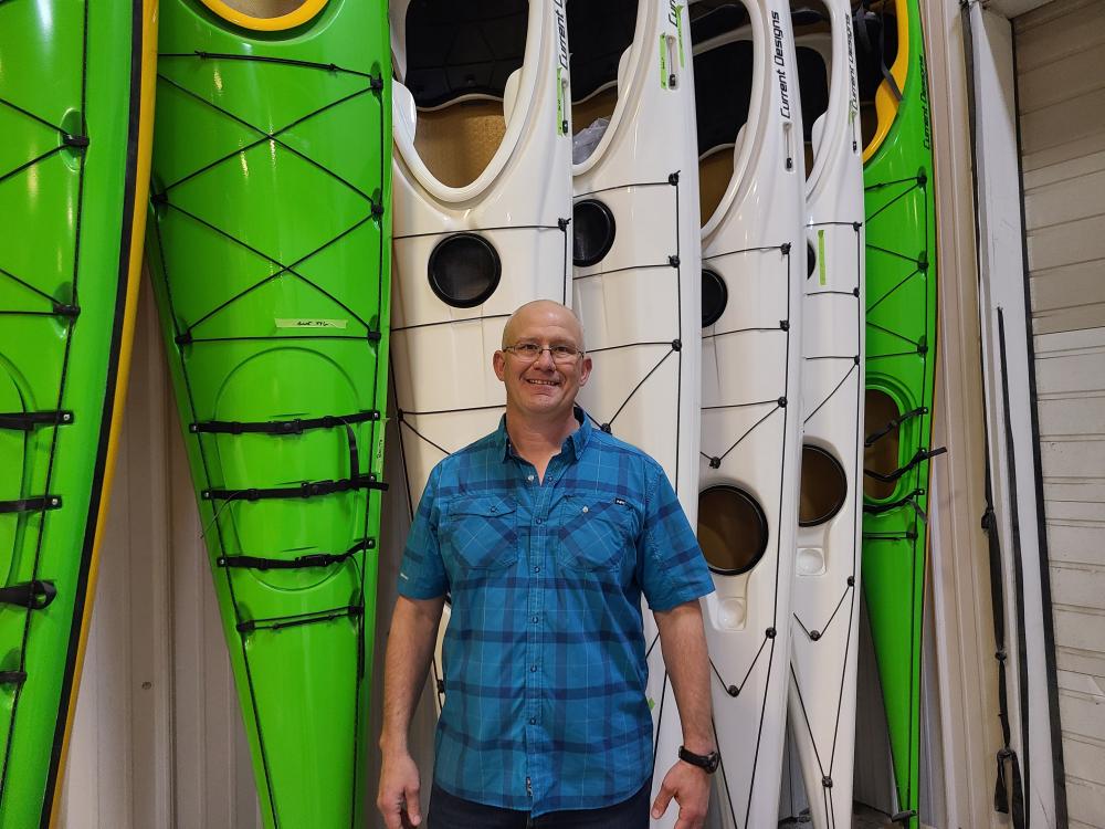 an image of Brian from Wenonah standing in front of kayaks