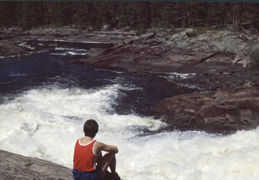 A man sits on a rock directly overlooking Basswood Falls