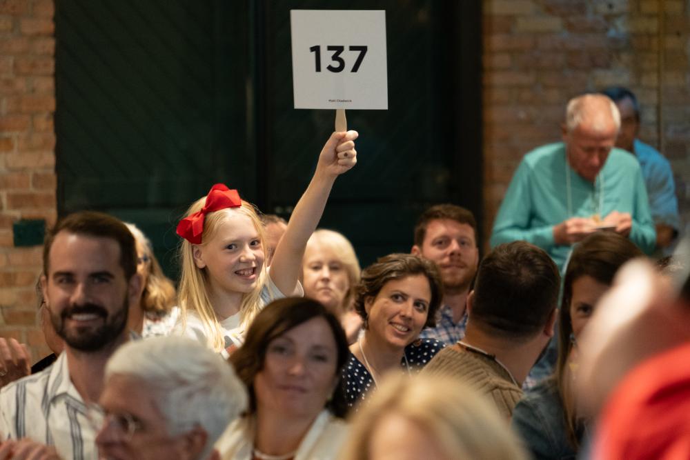 Young girl holding bid sign 