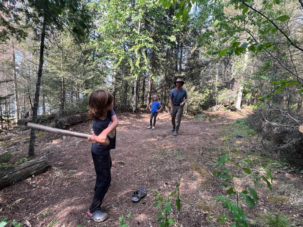 Kid with a bat made from a stick ready to hit a pine cone