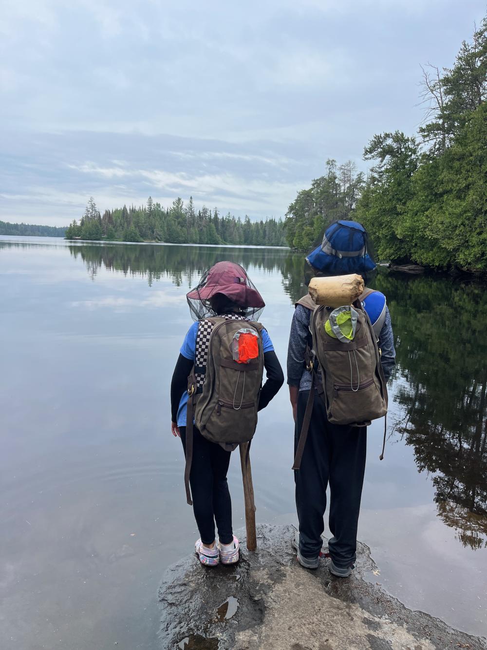Kids standing near water with backpacks