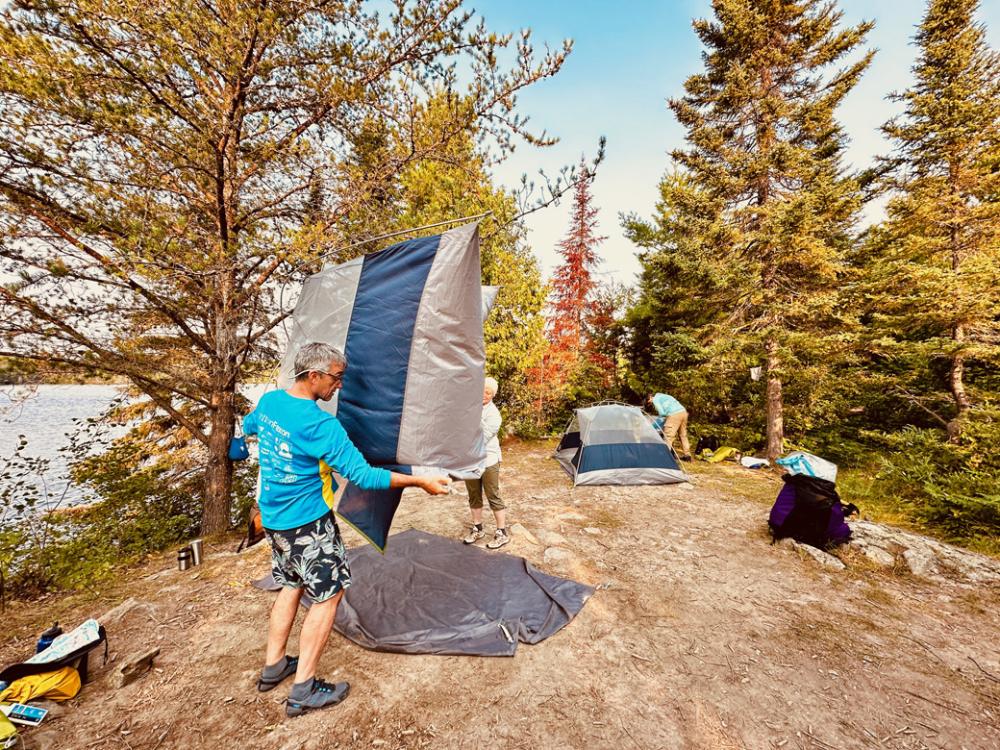 Two people are putting away their tent. 