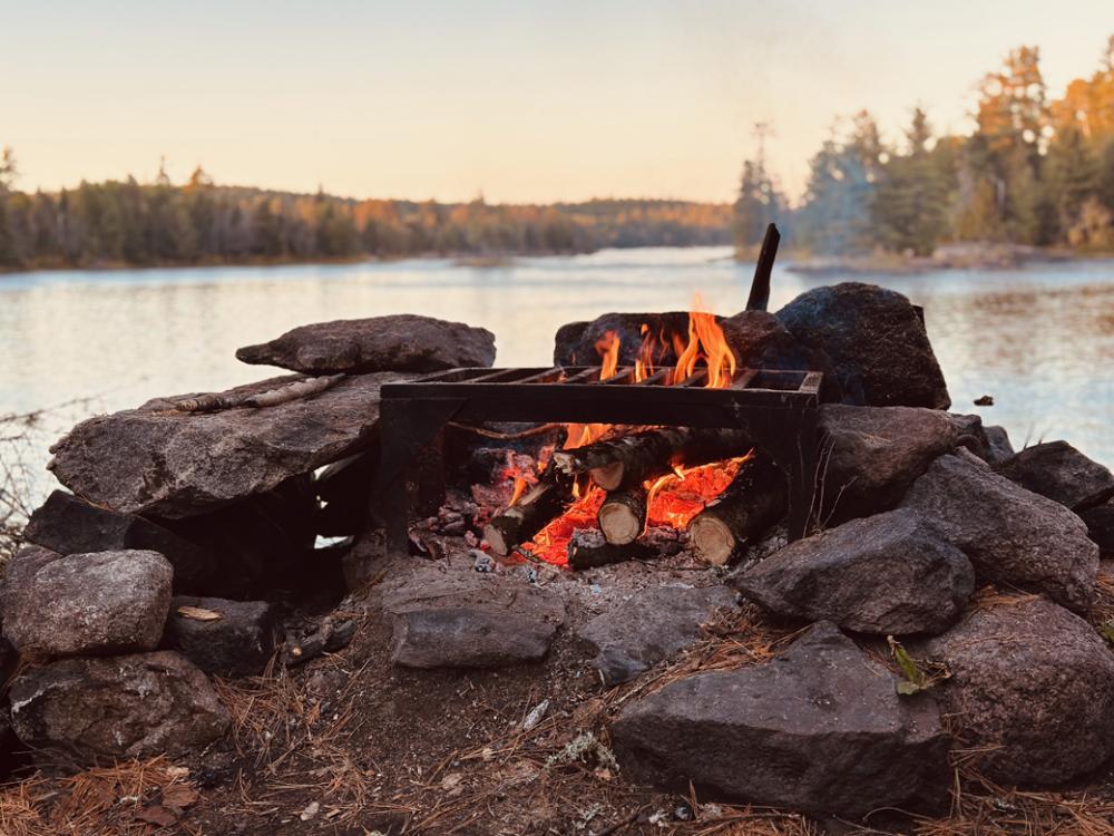 A small campfire burns in a firegrate surrounded by rocks. 