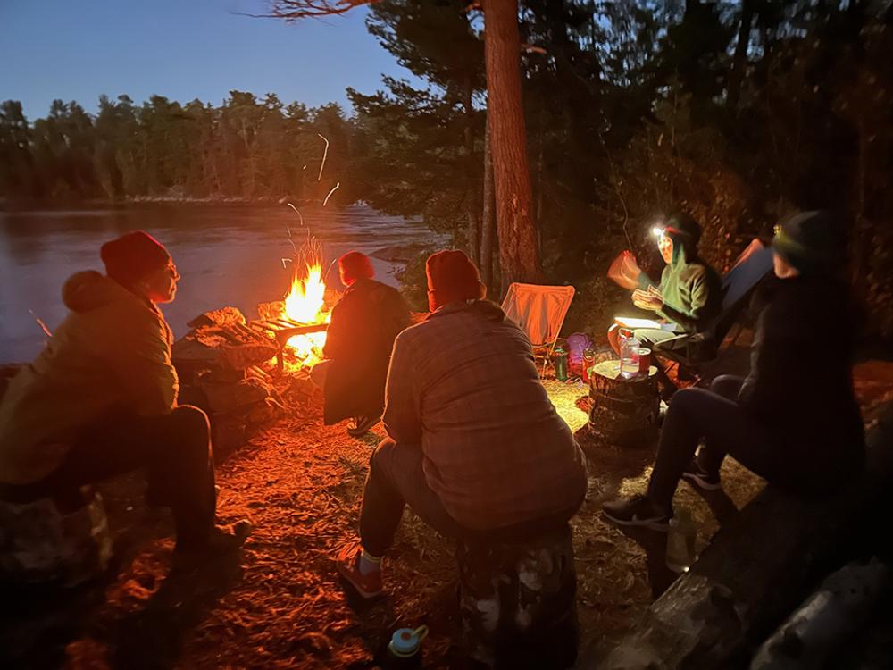 A group sites around the campfire while one person reads a story. 