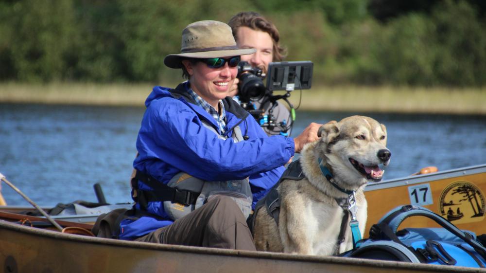 Amy Freeman, along with a four-legged friend, paddles in the stern of her canoe as the Freemans return from their Year in the Wilderness.