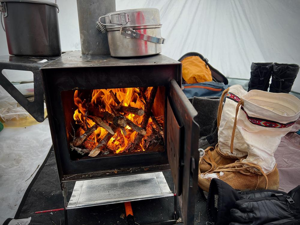 A small wood stove creates warmth and cozieness in the canvas hot tent.