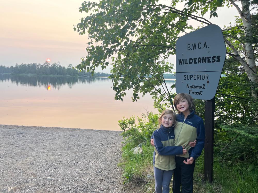Two kids in front of Wilderness sign during sunset