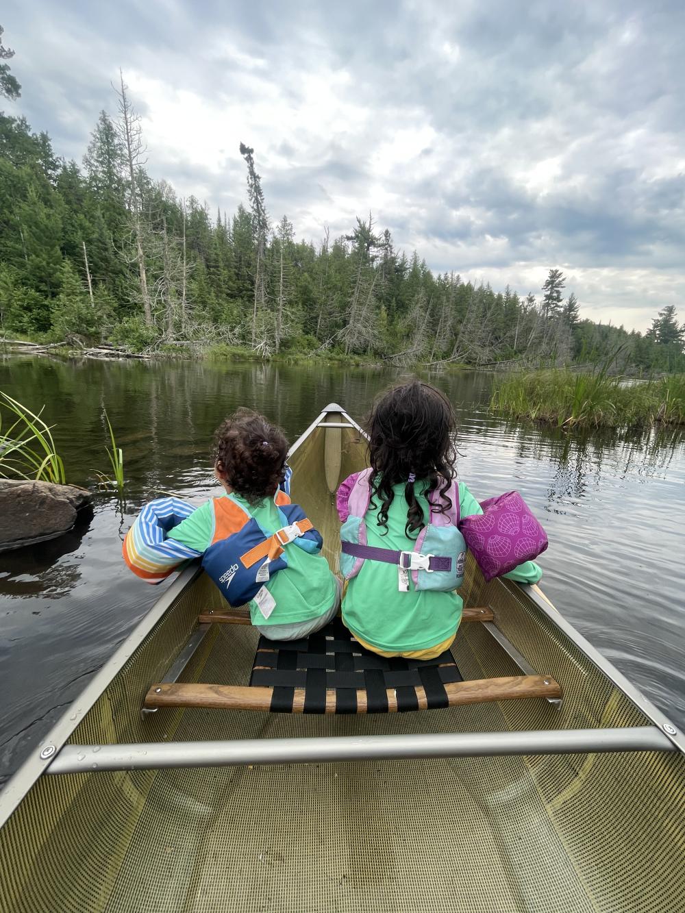 Two children sharing a seat in a canoe