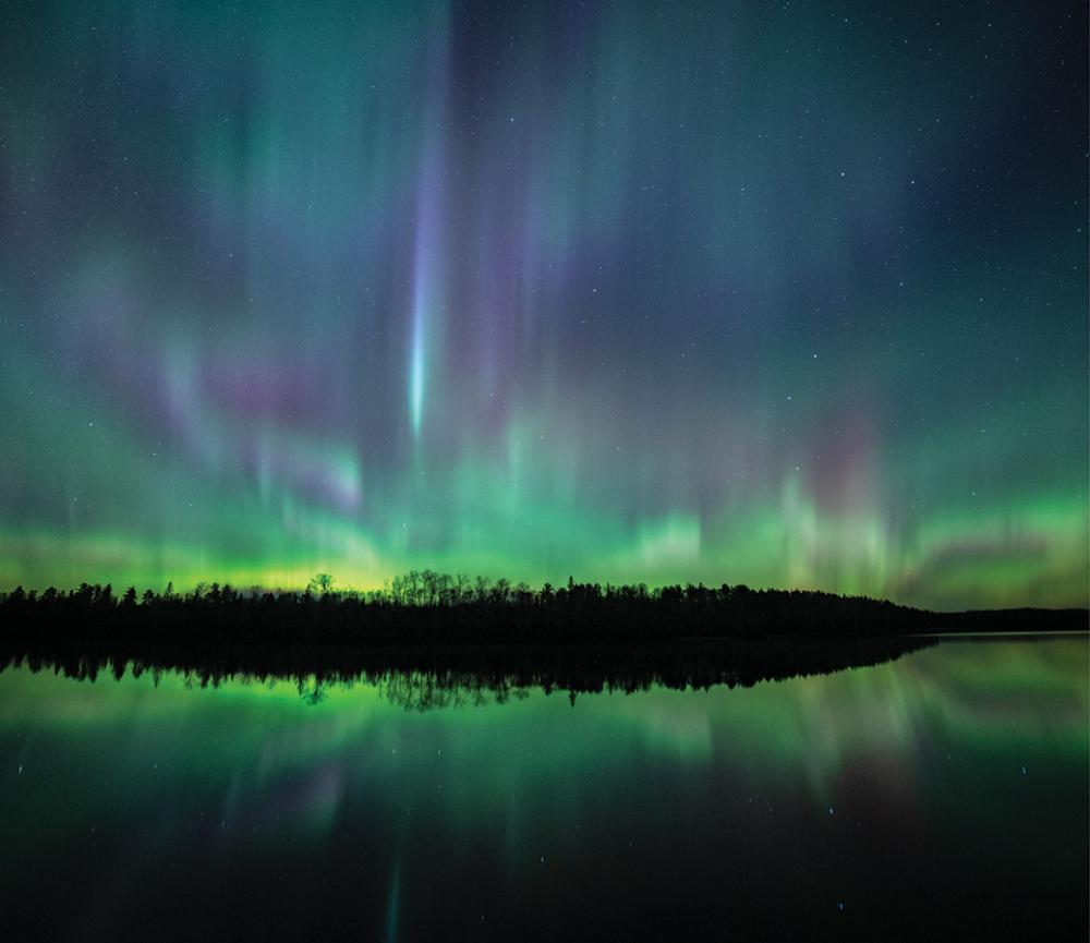 The aurora borealis (northern lights) dances over a Wilderness lake.