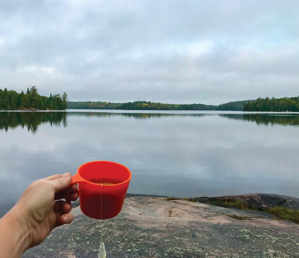 Person raising a glass near a wilderness lake photo Pam Wright