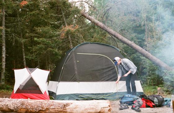 Photo of person picking up stick infront of two tents