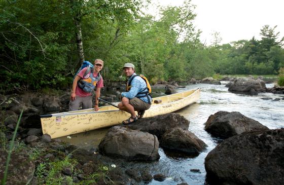 photo of Dave and Amy Freeman squatting next to a canoe on some rocks in the Boundary Waters