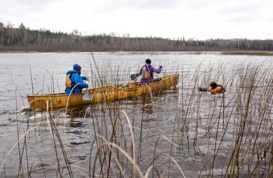 Dave and Amy Freeman paddling in a canoe with Nate Ptacek filming in the water