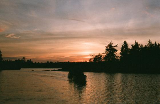 Silhouette of people canoeing into the sunset 