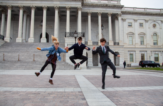 Photo of 3 kids jumping up and clicking their heels infront of a building in Washington DC