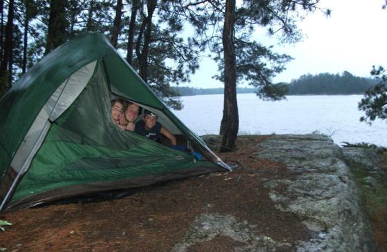 Photo of three boys peaking head out of green tent in Boundary Waters