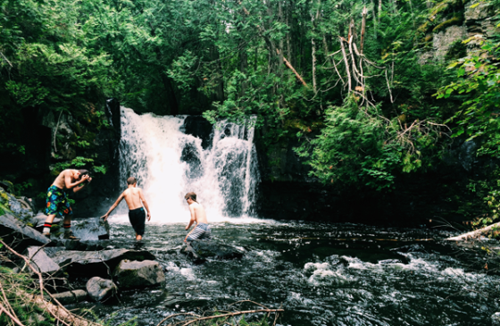 Photo of three youth standing in a waterfall in the Boundary Waters