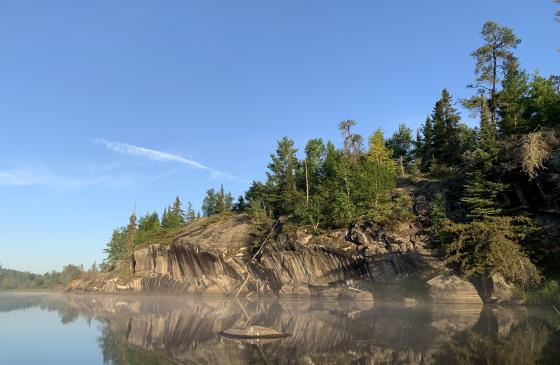 Clif rocks reflecting onto blue water