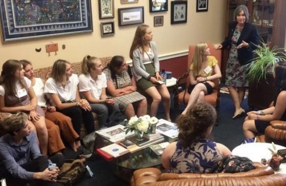 Photo of group of kids sitting down looking at Rep. Betty McCollum speaking to them