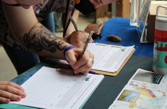 A close-up image of a hand signing a petition in support of a recommended 20-year ban on sulfide-ore copper mining near the Boundary Waters at a recent Save the Boundary Waters event 