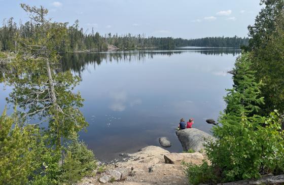 Kids sitting down by the water in the Wilderness