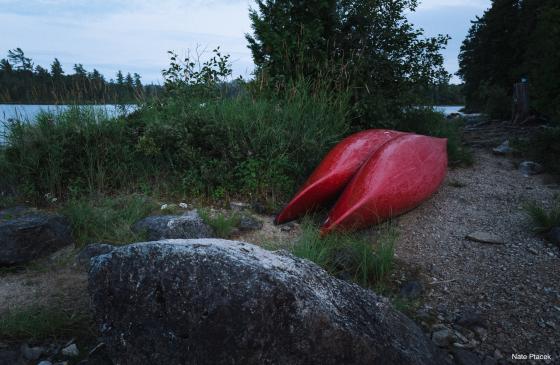 Two red canoes sit upside near a campsite in the Boundary Waters (Photo Credit: Nate Ptacek)