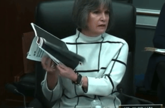 Photo of Rep. McCollum holding up blacked out pages