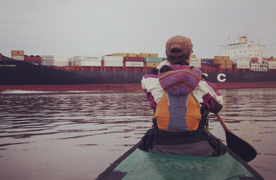 Photo of Amy Freeman paddling in a kayak towards a shipping barge