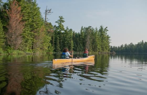 Two girls paddling in the Boundary Waters in a yellow canoe