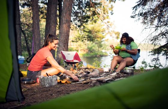 two people sitting at campsite around fire pit in daylight
