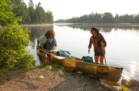 two people getting into a canoe on shore