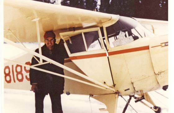 Photo of Bill Rom standing under an old school plane