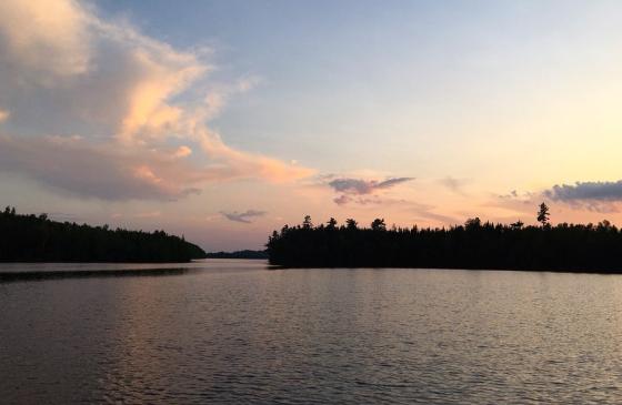Photo of Boundary Waters sunset with tree silhouettes on the horizon