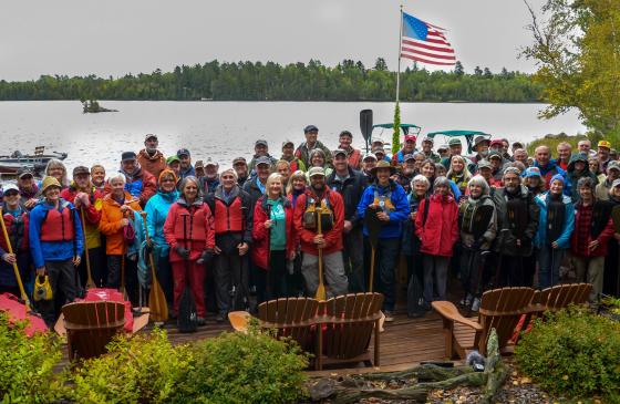 Large group of supporters holding up paddles standing near Boundary Waters