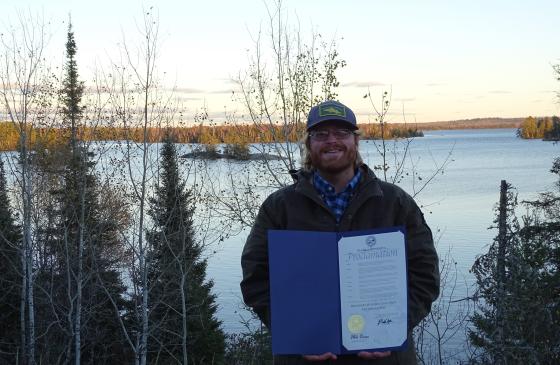 photo of a man holding the Boundary Waters proclamation infront of a snowy boundary waters