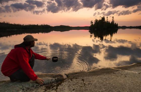 Dave Freeman dipping pot into lake at sunset