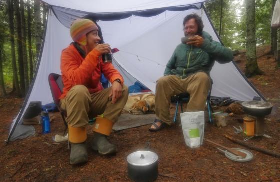 Photo of Amy and Dave Freeman sitting on chairs under a tent eating a camp meal