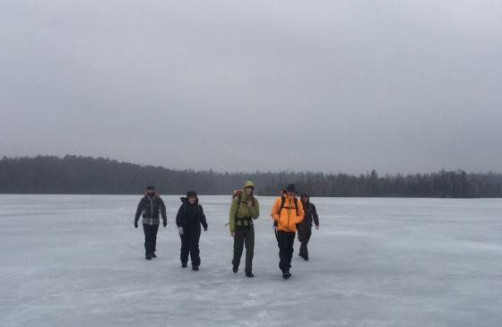 Photo of 5 people walking on frozen lake in Boundary Waters