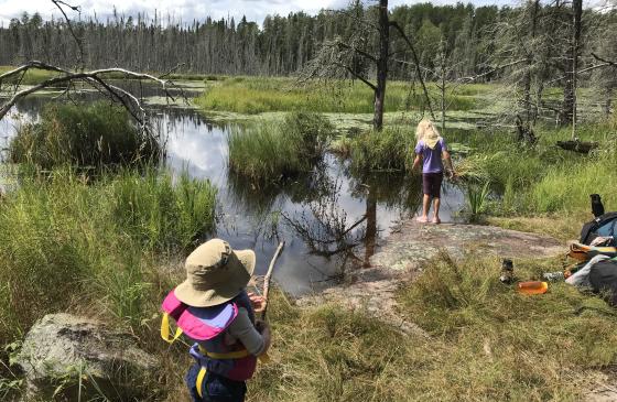 pictures of two kids standing on the shore next to a lake