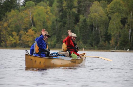 Dave and Amy Freeman waving in a canoe