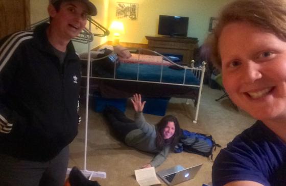 Photo of 2 people smilimg selfie style and one person lying on the floor smiling