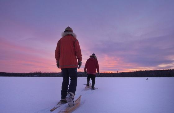 Photo of 2 people snowshoeing over frozen lake 