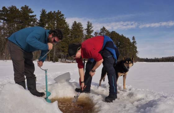 Photo of Amy and Dave Freeman leaning over an ice hole in a frozen lake