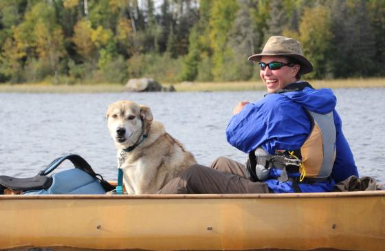 Photo of Amy Freeman paddling a canoe with a sled dog on the South Kawishiwi River