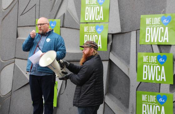 Photo of 2 men standing infront of We love the BWCA signs holding a mega phone